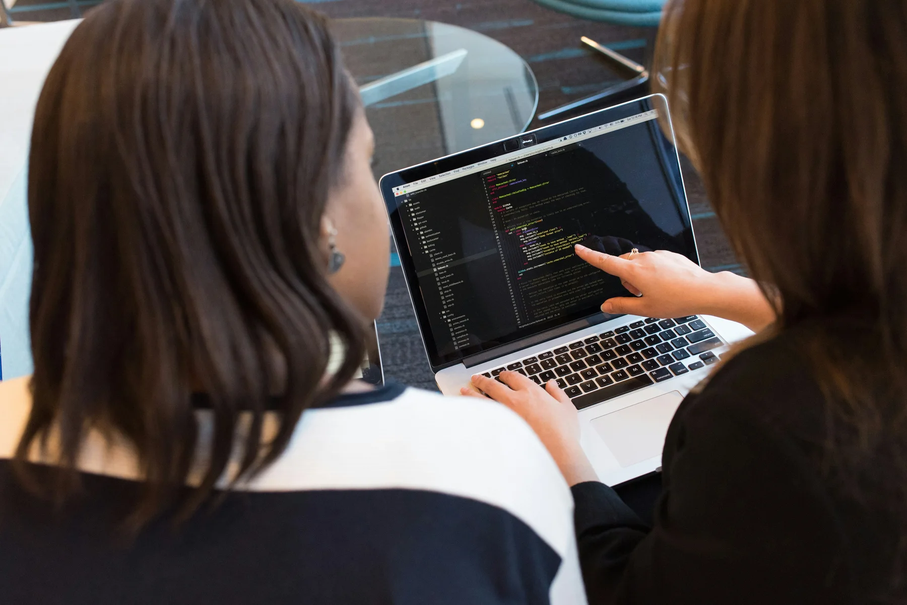 Deux professionnelles informatiques consultent du code sur un ordinateur portable.
